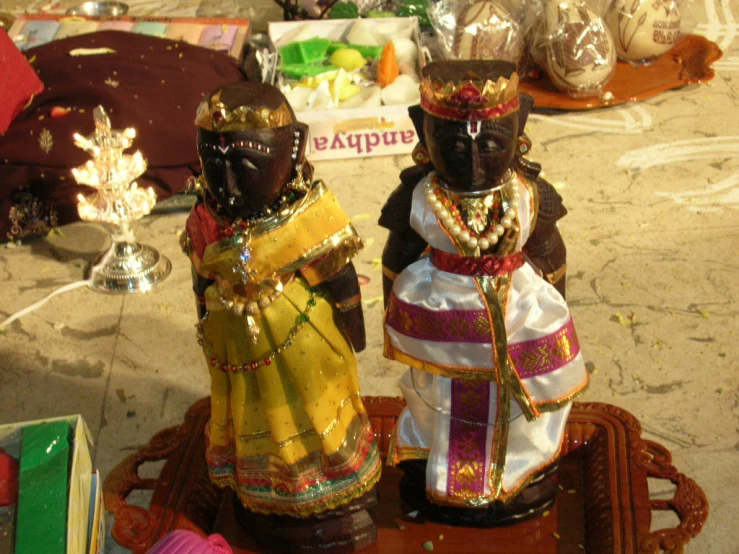 two small black figures sitting on top of a table