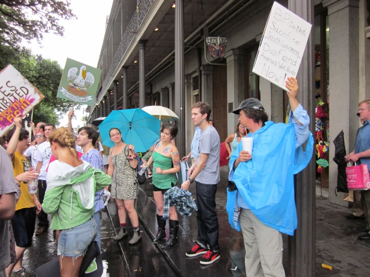 protesters holding signs and umbrellas outside on a city street