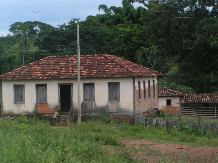 an old building sitting in the middle of a lush green field