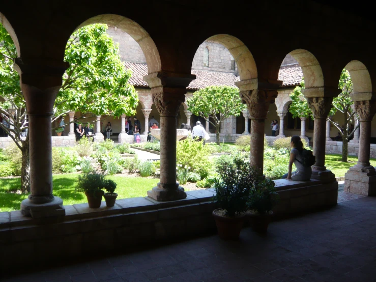 a courtyard with green plants and people walking