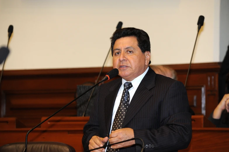 a man in a suit speaking into microphones at a podium