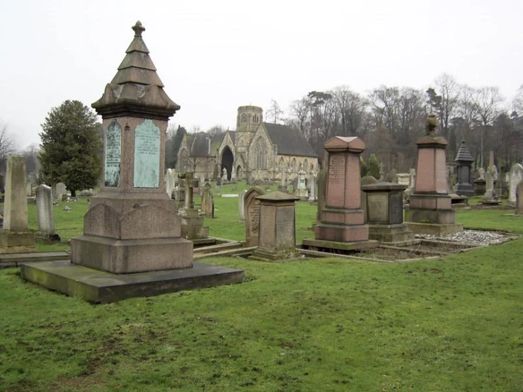 several stone headstones stand in a grassy cemetery