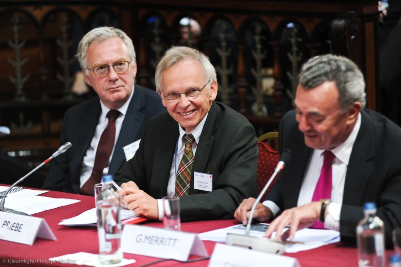 four men sitting at a table in suits