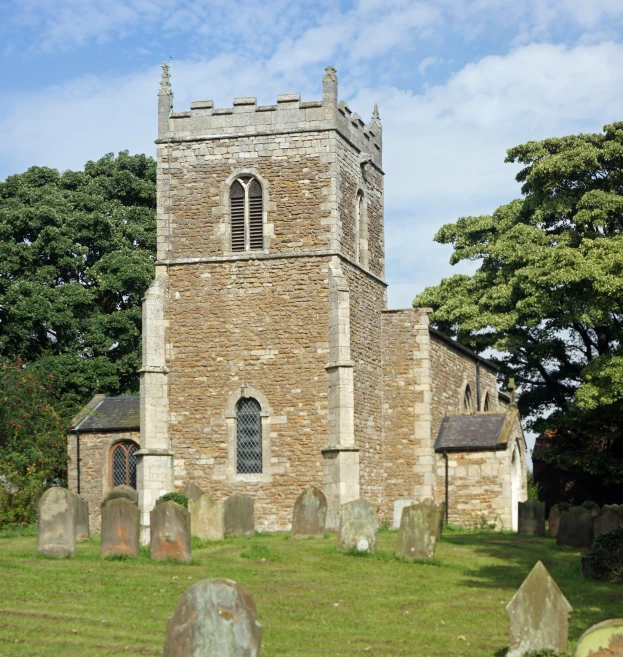a tall church tower surrounded by graves on a green field