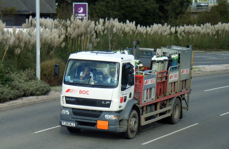 the truck is driving down the street with many things on it