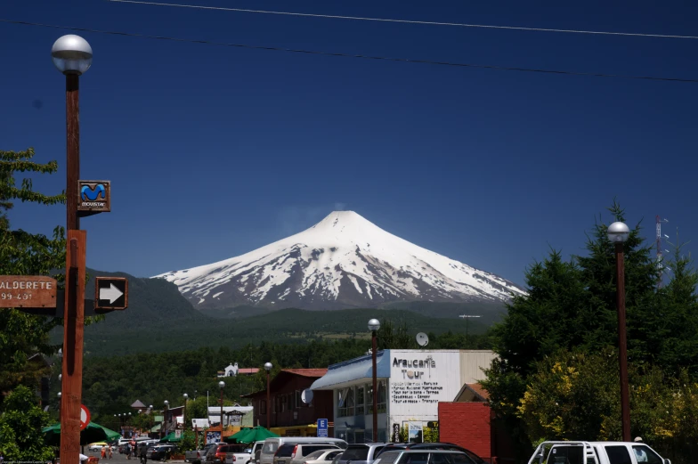 the mountain is white in the background as cars drive down the street