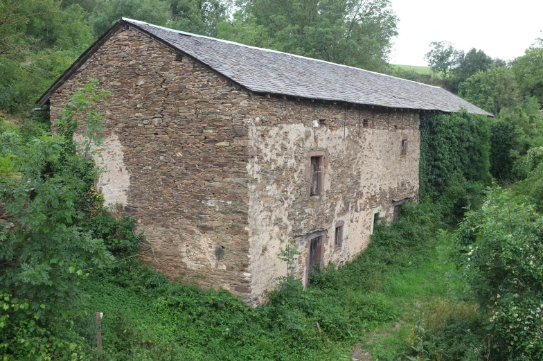 an old brick barn on the side of a forest