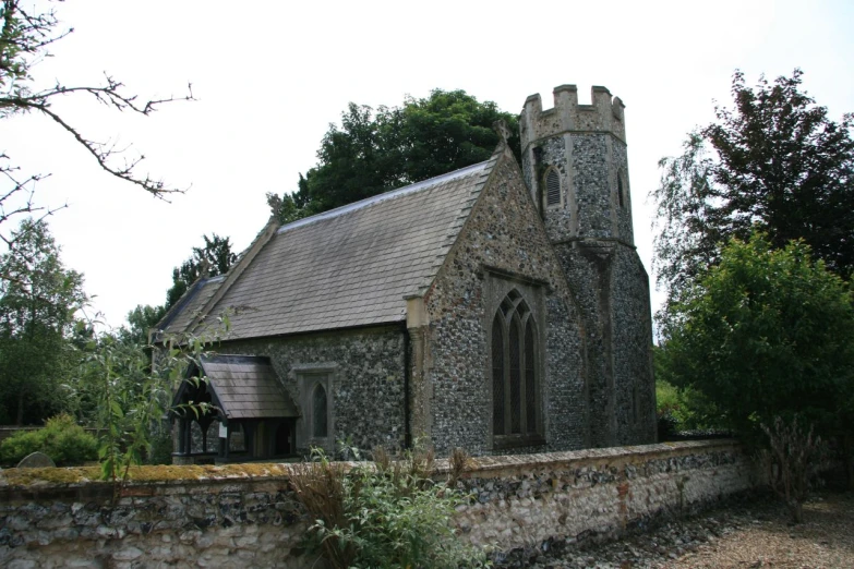 a stone church surrounded by some trees and bushes