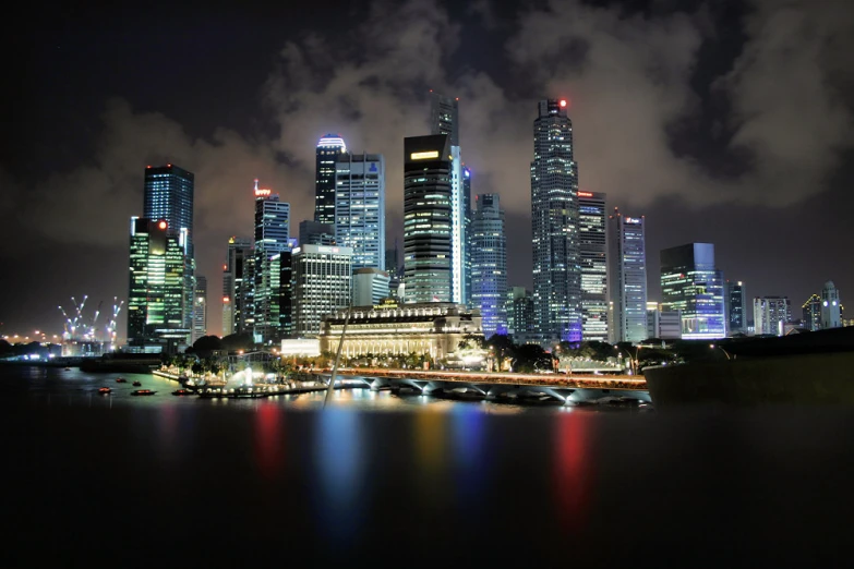 city skyline at night overlooking the river and boats