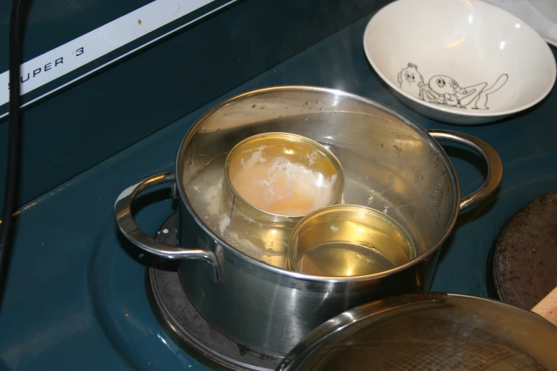 three pans and a bowl sit on the burner