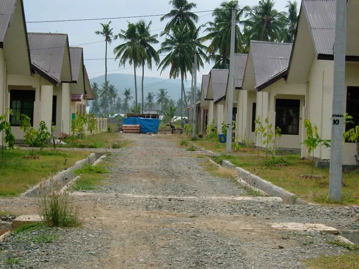 a dirt road that leads to several small buildings