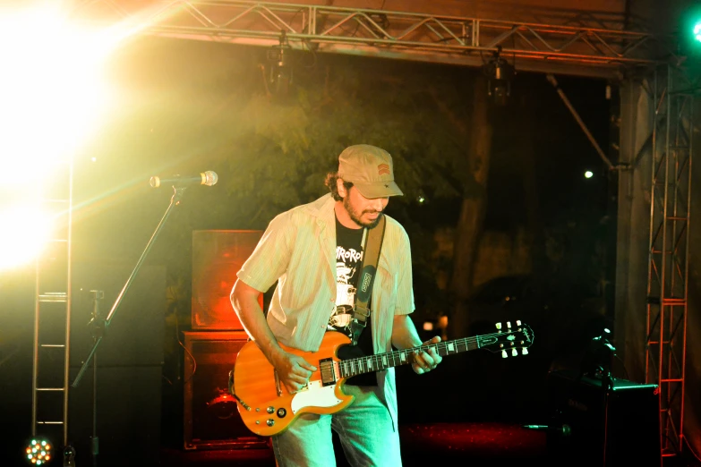 a man plays guitar while standing in front of some lights
