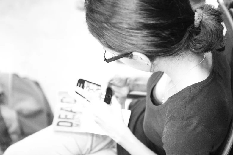 a woman looks at her cell phone while sitting