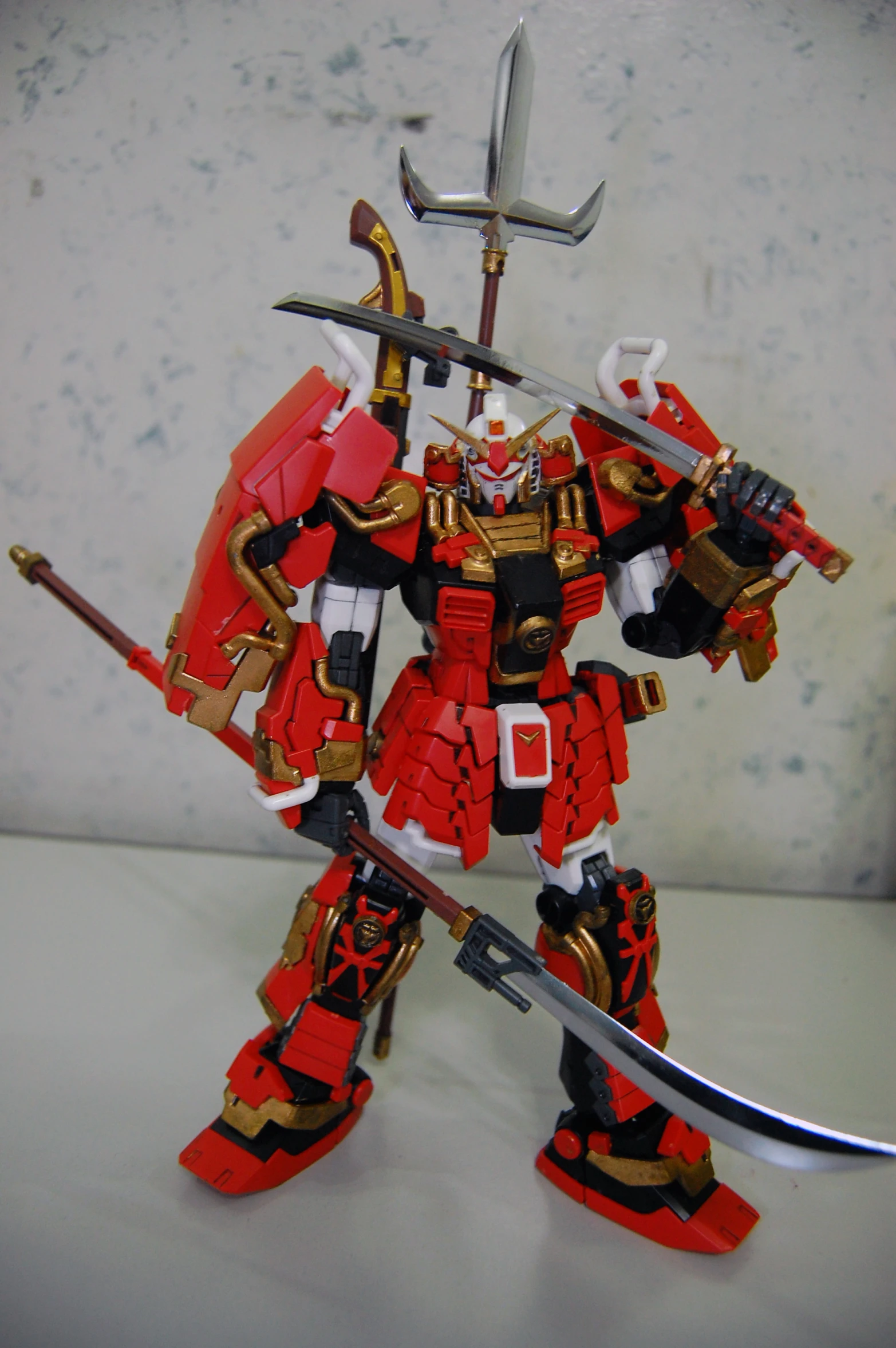 toy action figure of a red and gold armor type robot holding two swords