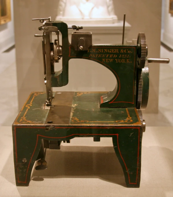 a green antique sewing machine sitting on top of a white table