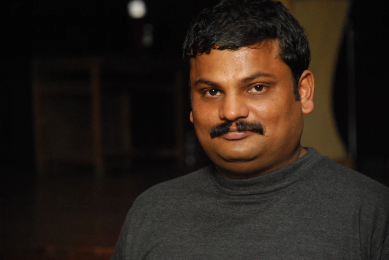 a man wearing a gray turtle neck shirt has a moustache