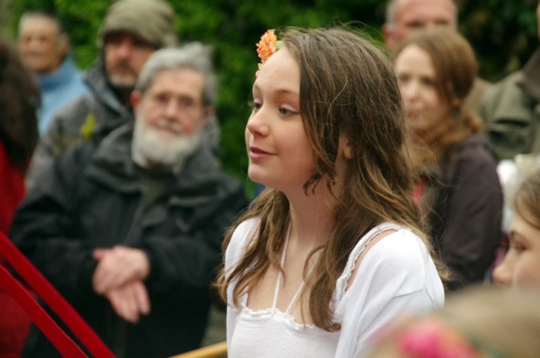 young woman with flowers in her hair sitting among a group of people