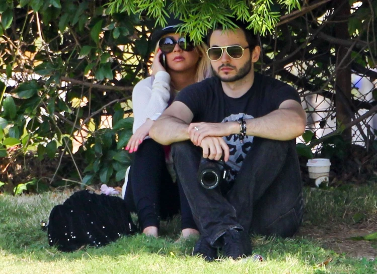 a couple taking a picture with their camera near a tree