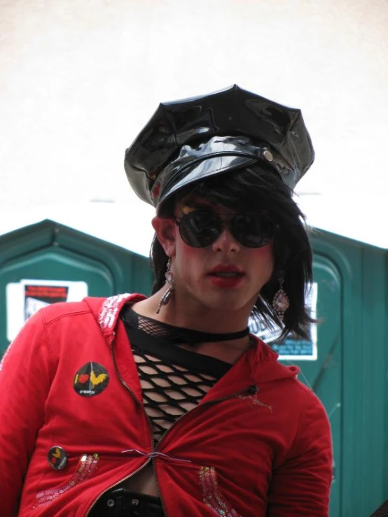 woman with a red shirt and black hat standing in front of a garbage can