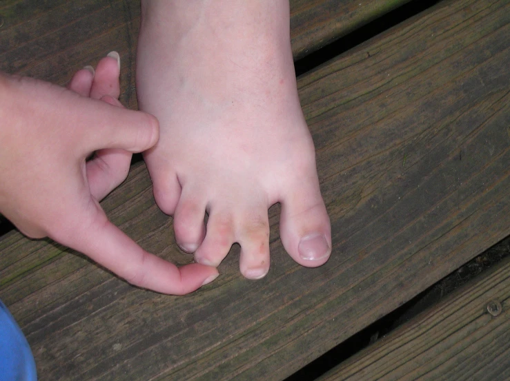 two bare feet hold hands on a wooden surface