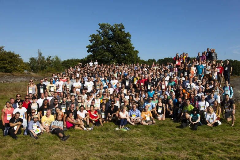 large group of people standing and sitting in the grass