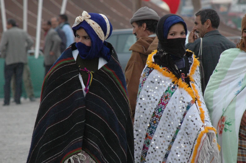 two women in colorful ponchoms walk down the street