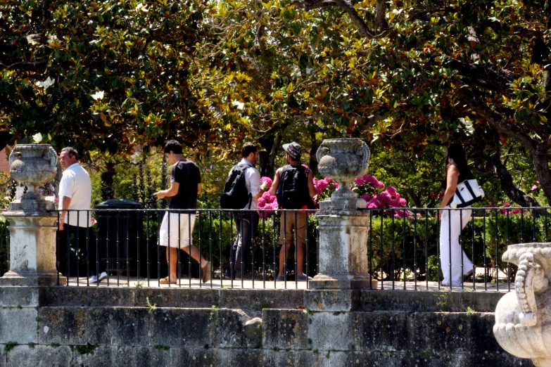 the people are standing on the side of the bridge looking over