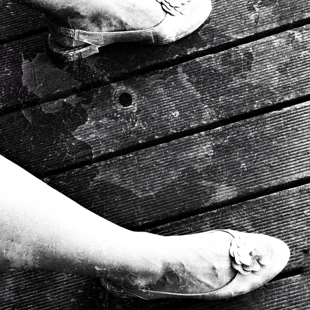 a pair of legs and shoes of someone's left foot on a pier