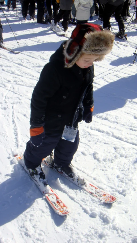 small  standing on the snow with skies and gloves