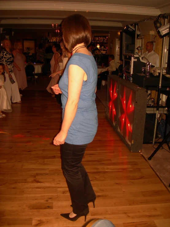 a woman is standing on a wooden floor while a band performs behind her