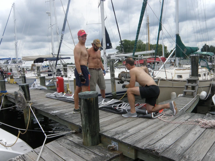 three men on a dock and some are using ropes