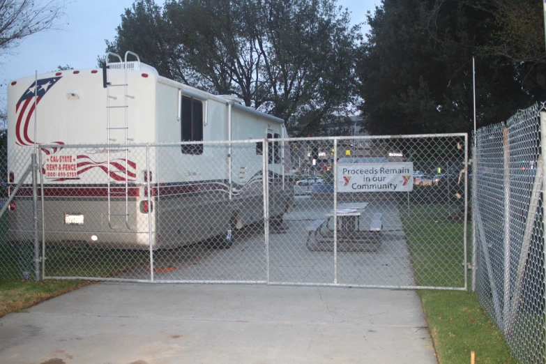 two rvs parked behind the fence of a chain linked fenced in area
