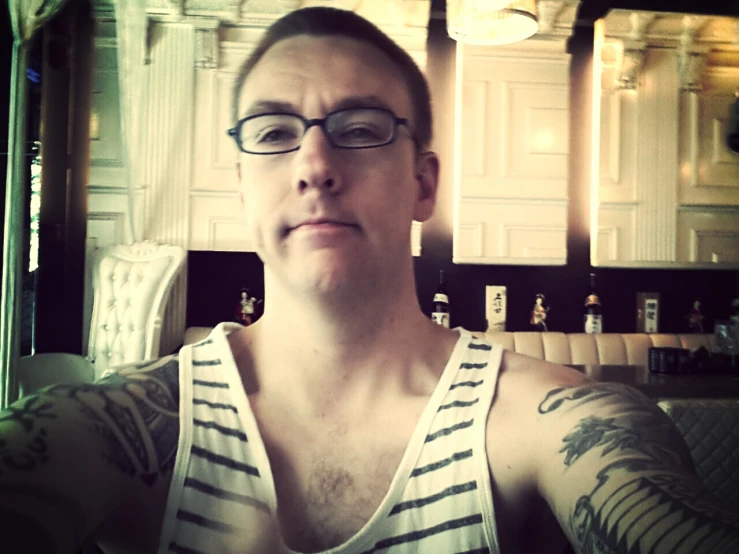 a man with glasses and tattoos on his arm posing for the camera