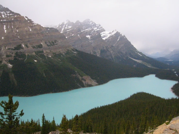 a valley with a lake surrounded by trees and mountain tops