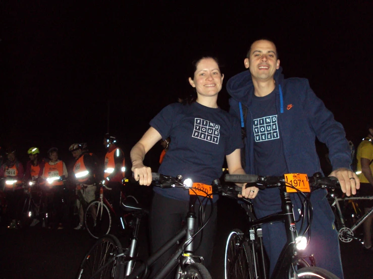 a couple of men in matching shirts standing on their bikes