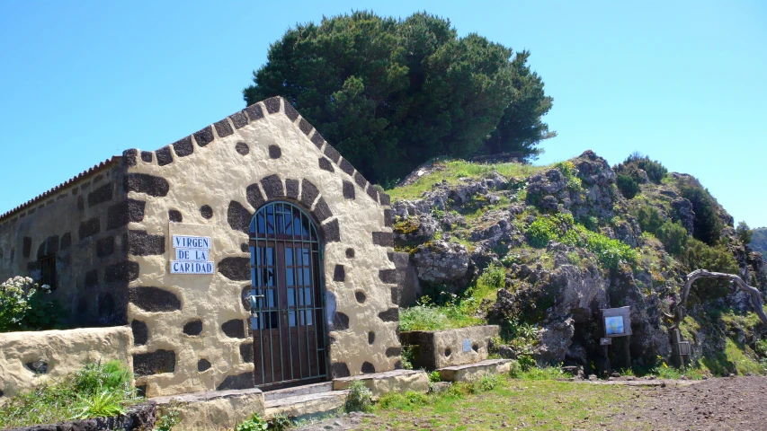 an old stone building sitting on the side of a hill