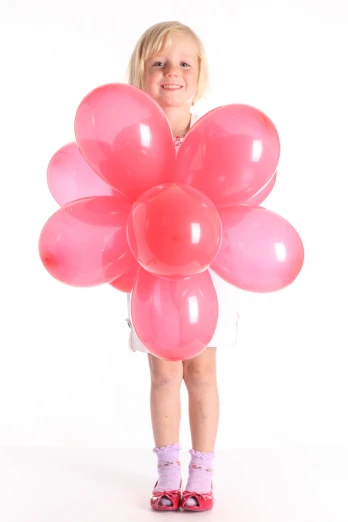 a little girl holding a large bunch of balloons