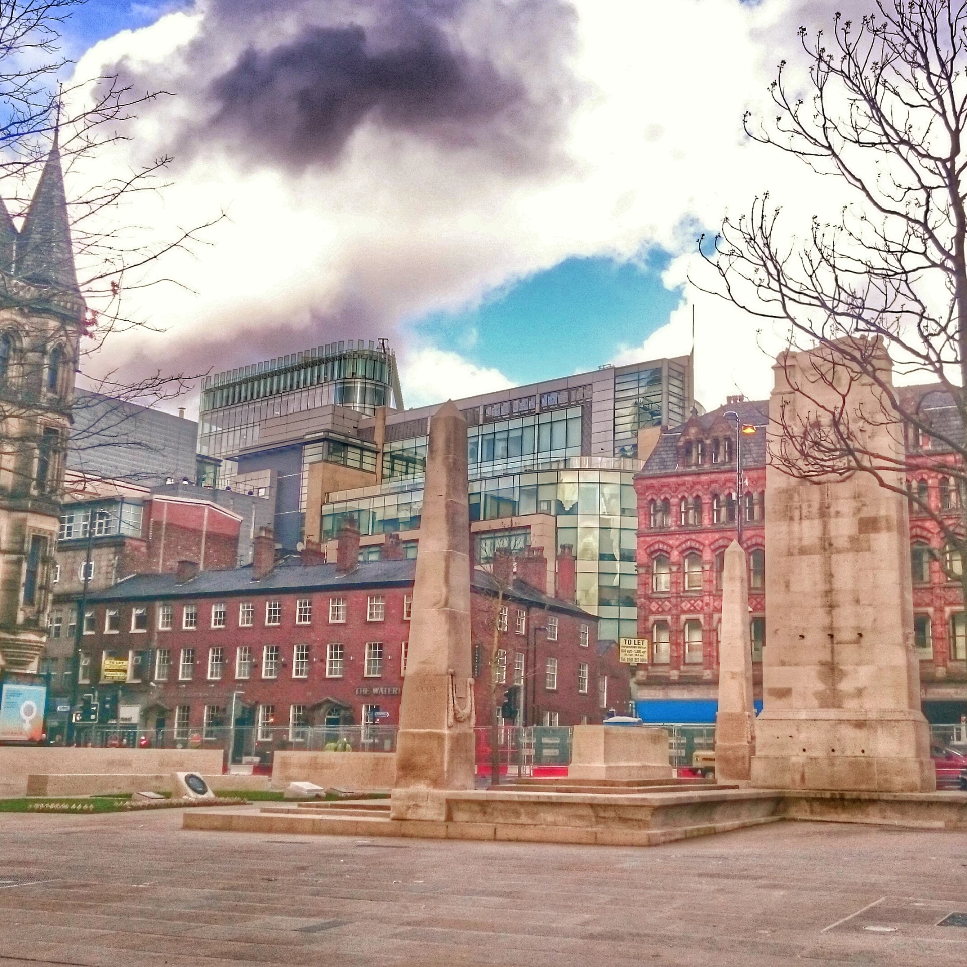 a square with many tall buildings and some very large trees