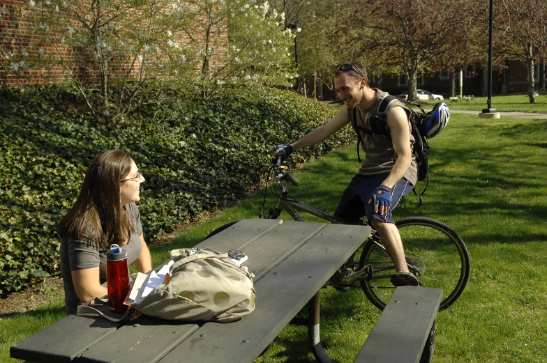 a man and woman sit on a bench near a picnic table