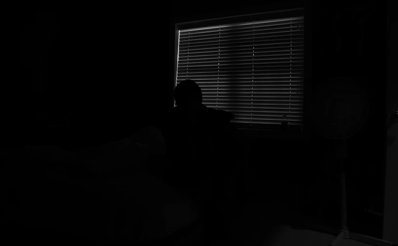 dark silhouette of a woman sitting in front of a window