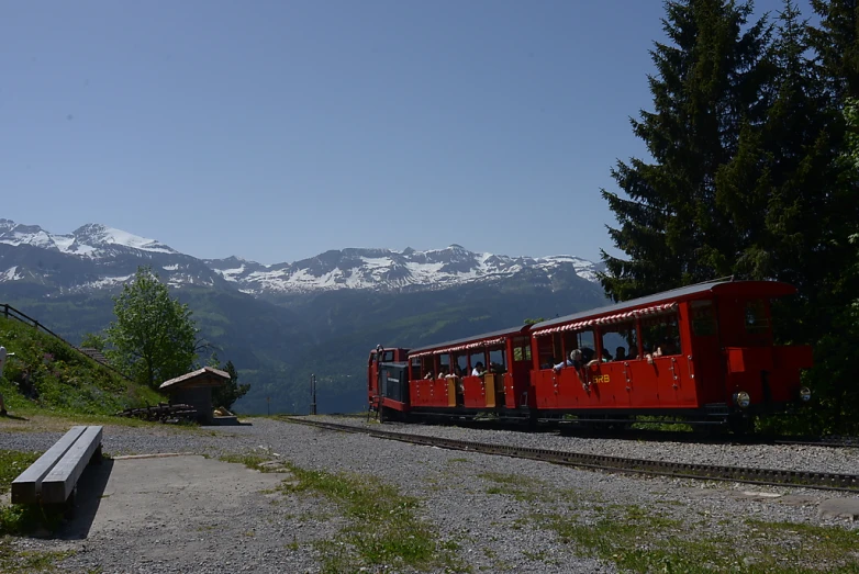 a small train traveling down tracks surrounded by mountains