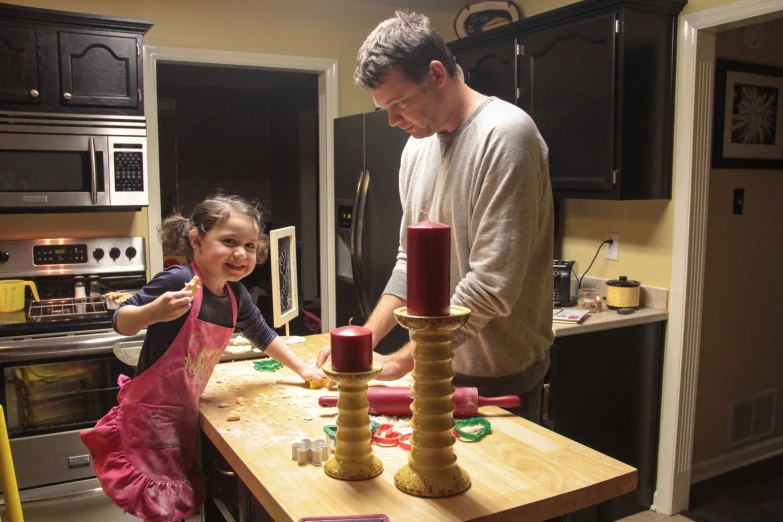 a man standing over a little girl at a kitchen counter