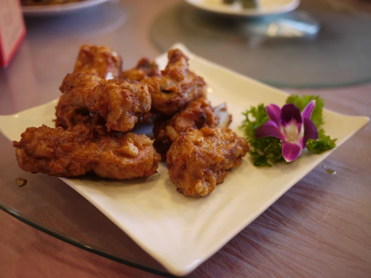 a plate of fried meat next to a flower and other plates