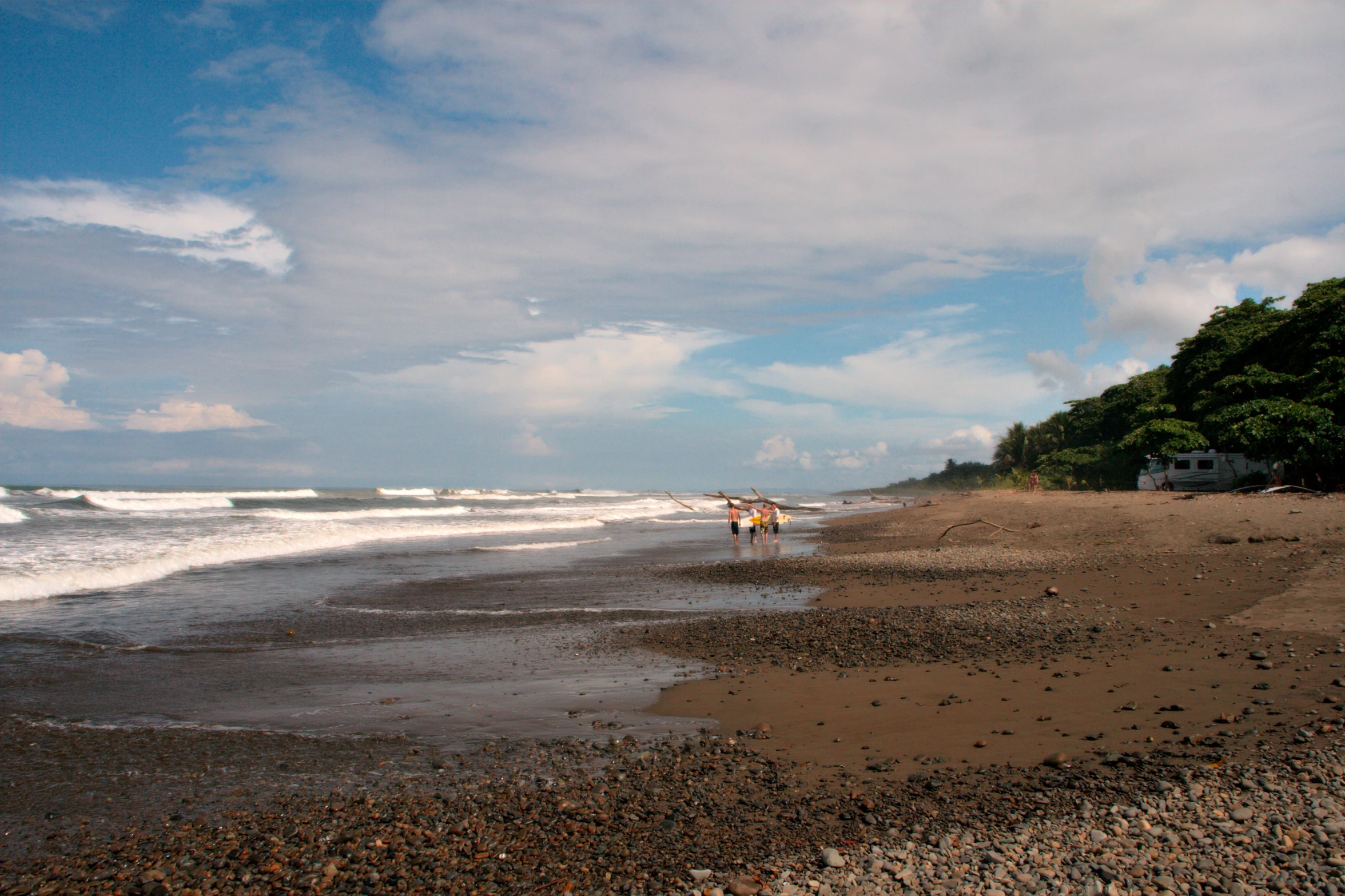 two people walking on a beach near the ocean