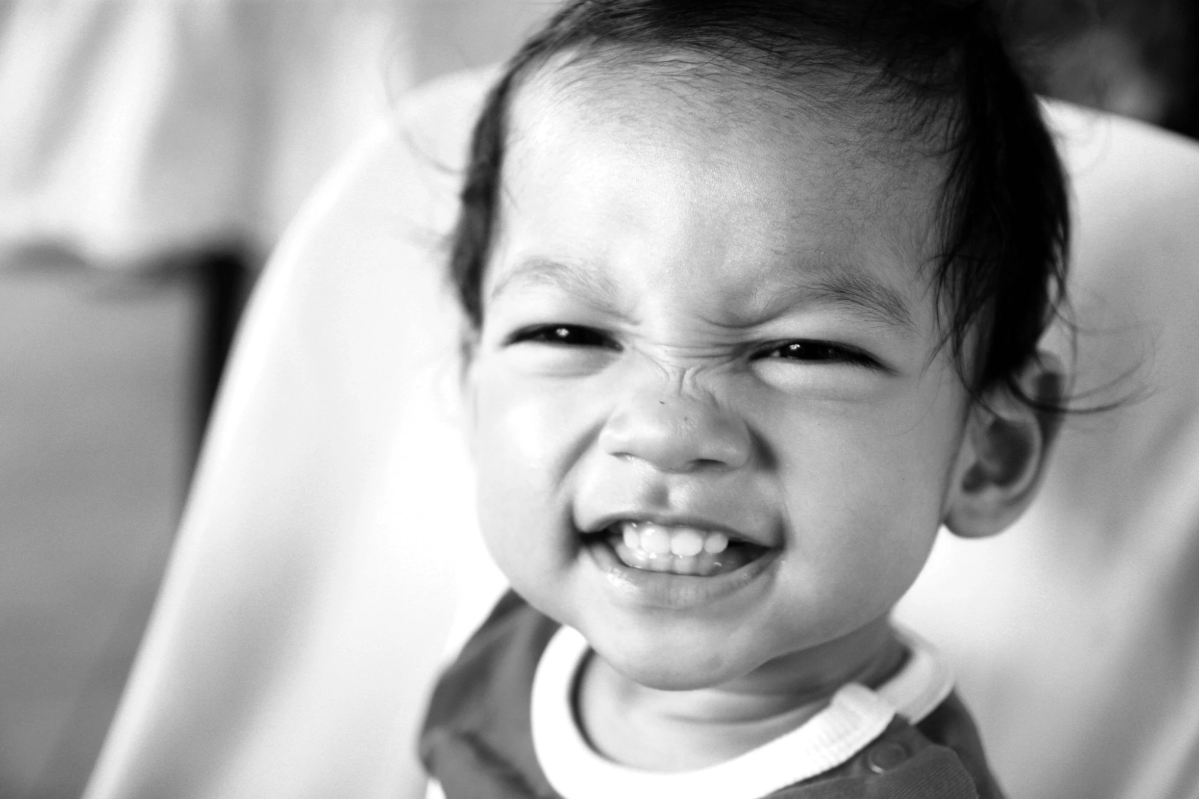 a smiling little  sitting in a chair with his mouth open