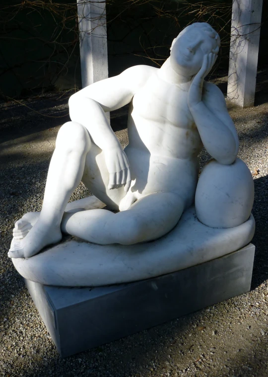 a sculpture of a man sitting on the ground