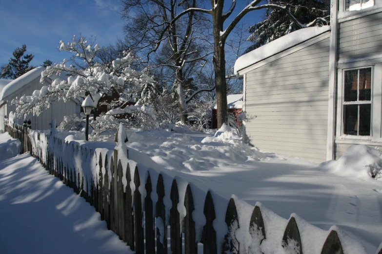 snow covered fence surrounding an old wooden building