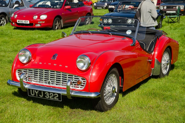 a very nice looking red car parked in the grass