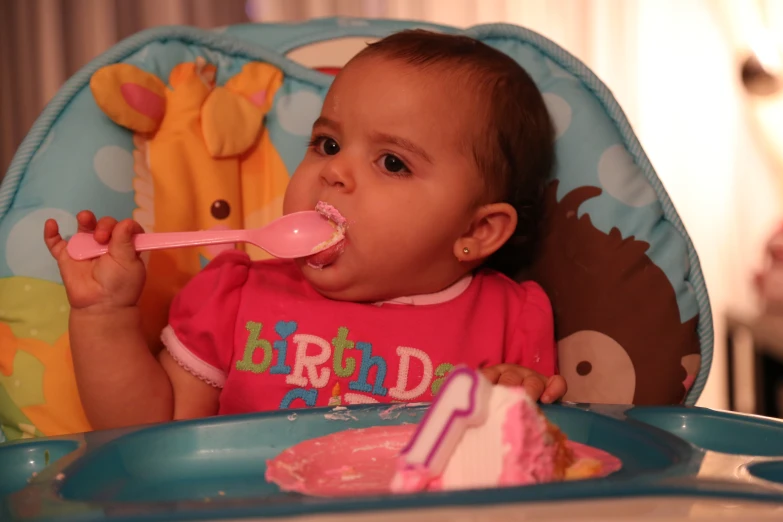 a baby sitting in a highchair eating cake