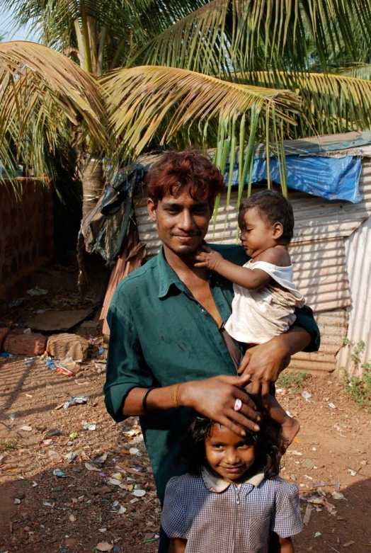 a man is standing in the middle of his village and a woman holds onto his child